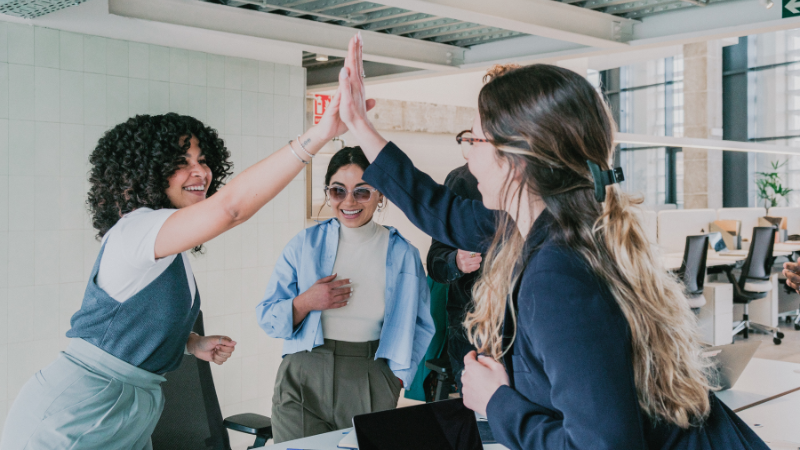 Women in business meeting, celebrating success with a high five.