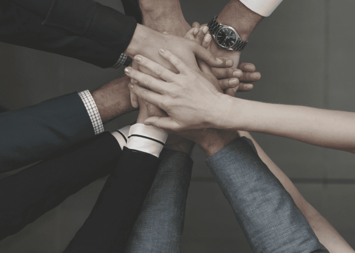 Group of diverse business people putting their hands in the center showing teamwork