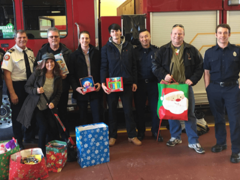 A group of PeopleToGo employees donate Christmas toys at a fire hall