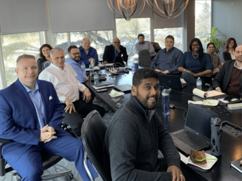 PeopleToGo employees sitting around a meeting table looking happily at the camera