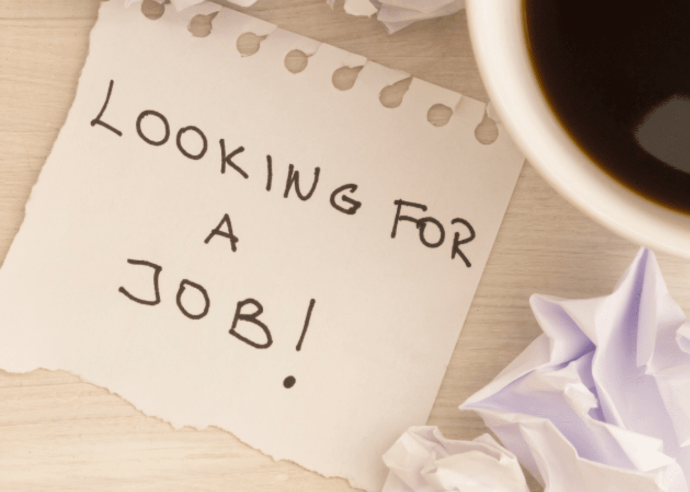 A journal page written with the words: Looking for a job, beside a cup filled with coffee