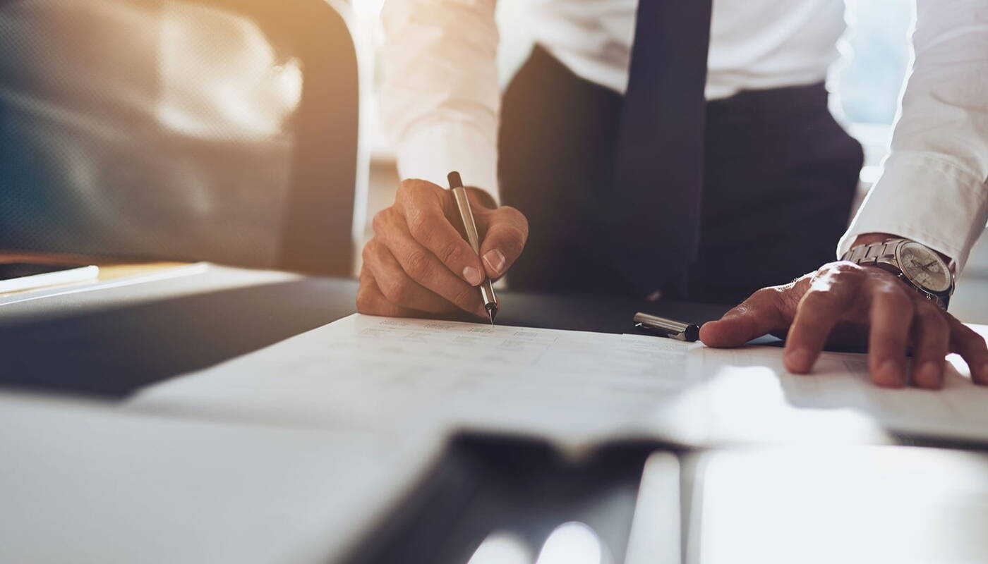 Well dressed businessman signing a document on a table 
