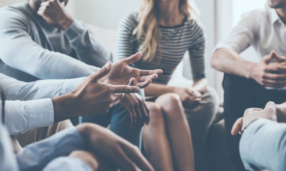 Business people having a discussion in a circle, a man is emphasizing an comment with his hands