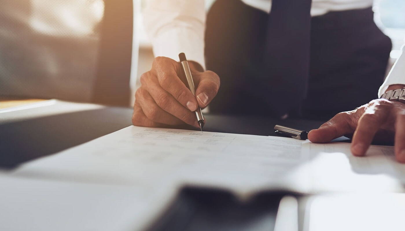 Well dressed businessman signing a document on a table 