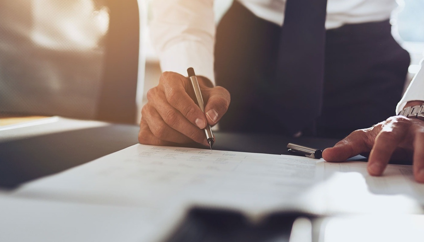 Well dressed businessman signing a document on a table