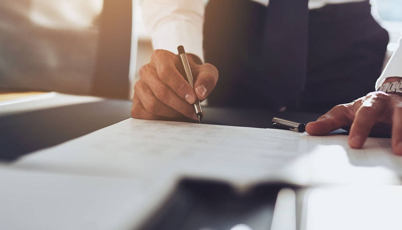 Well dressed businessman signing a document on a table 